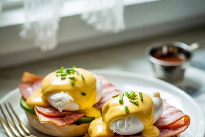 A freshly prepared plate of eggs benedict served with hollandaise sauce and garnished with herbs