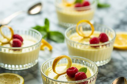 A glass serving of lemon posset topped with fresh lemon zest and mint