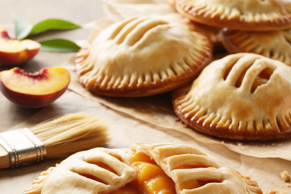Freshly baked peach hand pies with golden crusts on a cooling rack