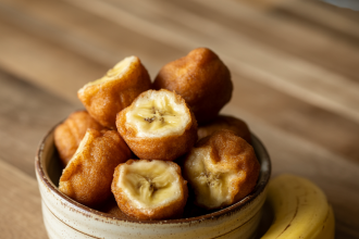 Freshly baked banana donut holes in a bowl on a wooden table