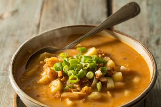 A steaming bowl of cajun potato soup with herbs and spices