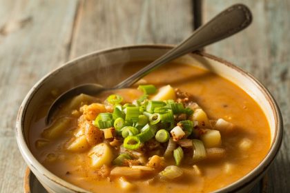 A steaming bowl of cajun potato soup with herbs and spices