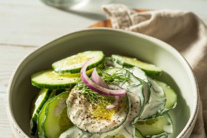 A bowl filled with creamy cucumber salad garnished with fresh dill