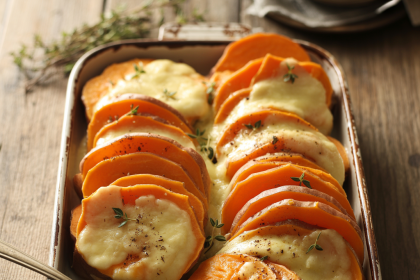 Baked scalloped sweet potatoes in a casserole dish with golden, crispy topping