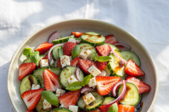 A bowl of vibrant strawberry cucumber salad with fresh herbs and dressing
